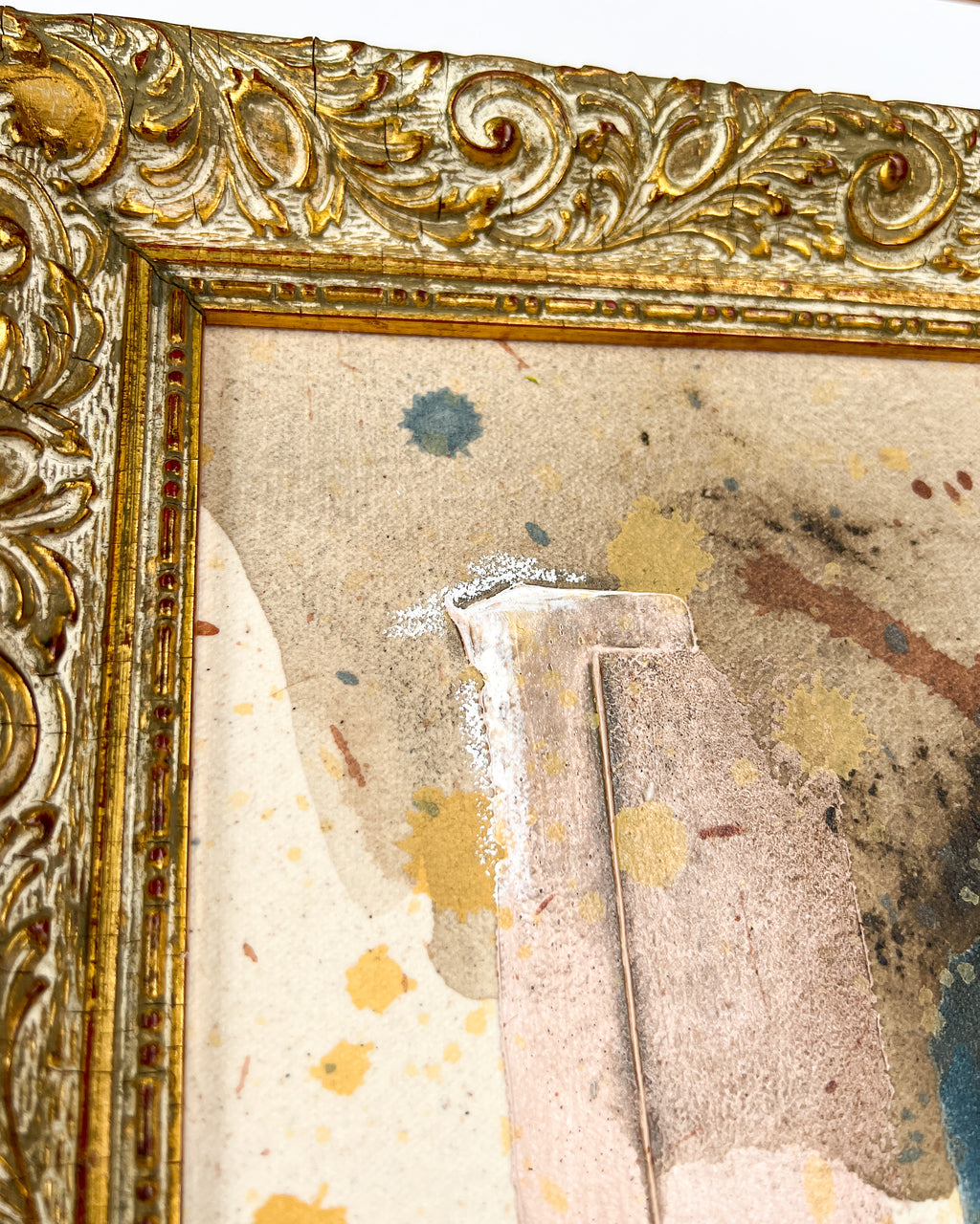 Close-up of an ornate gold frame with a textured, possibly aged background.