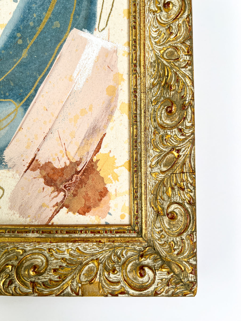 Close-up of an ornate gold frame with a textured painting inside
