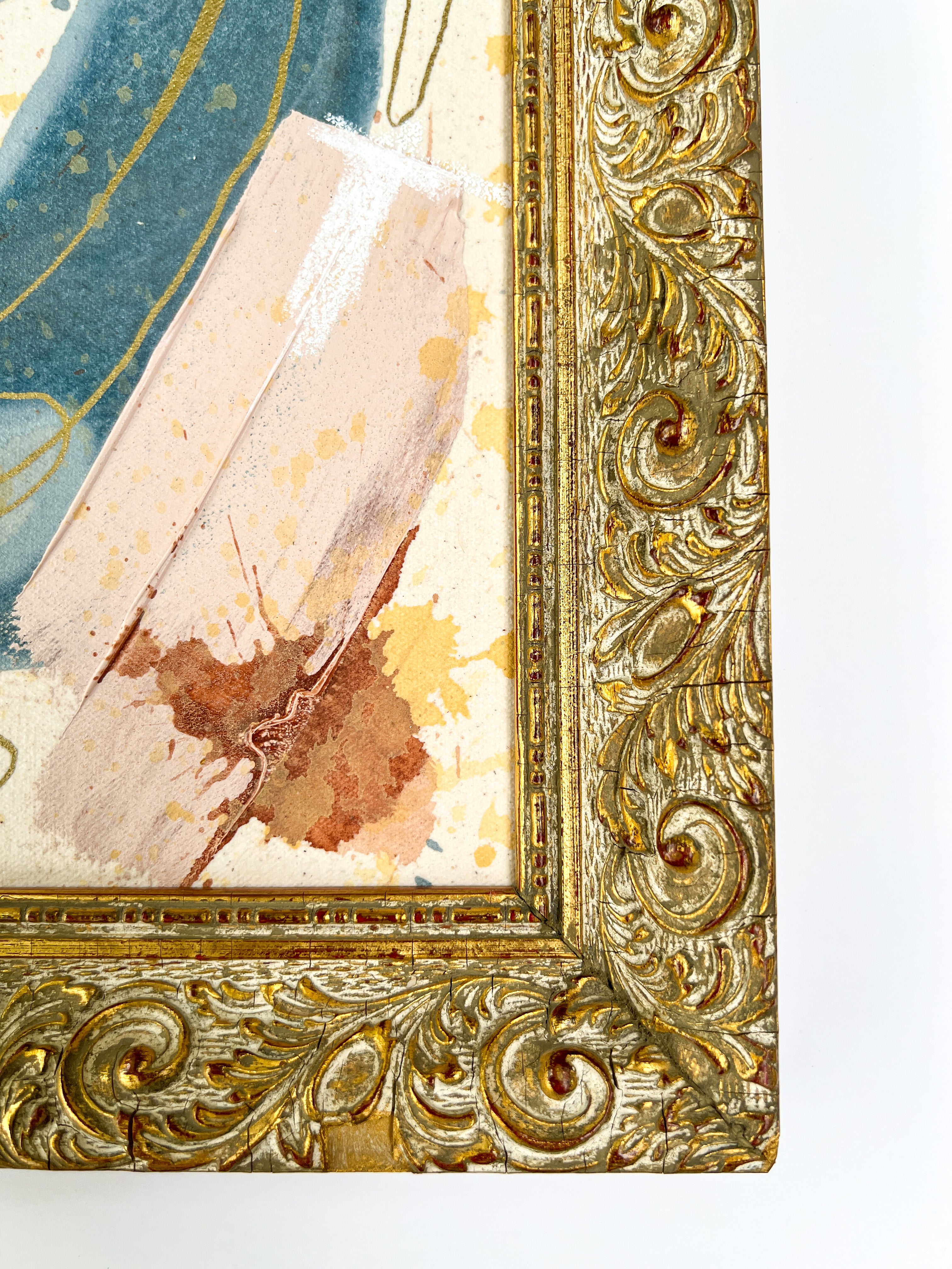 Close-up of an ornate gold frame with a textured painting inside