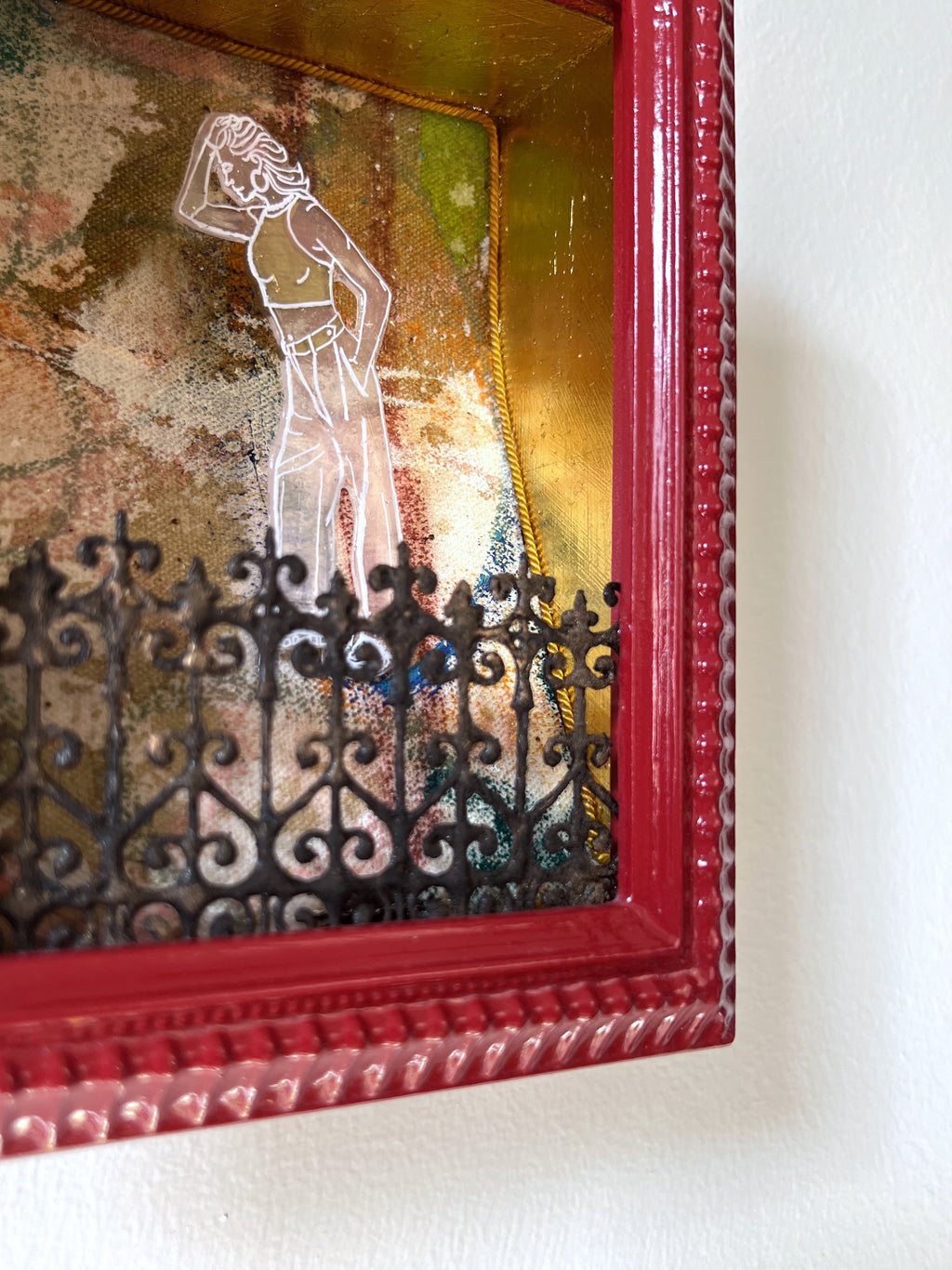 Decorative wall art with a red frame, woman silhouette, and fence design.