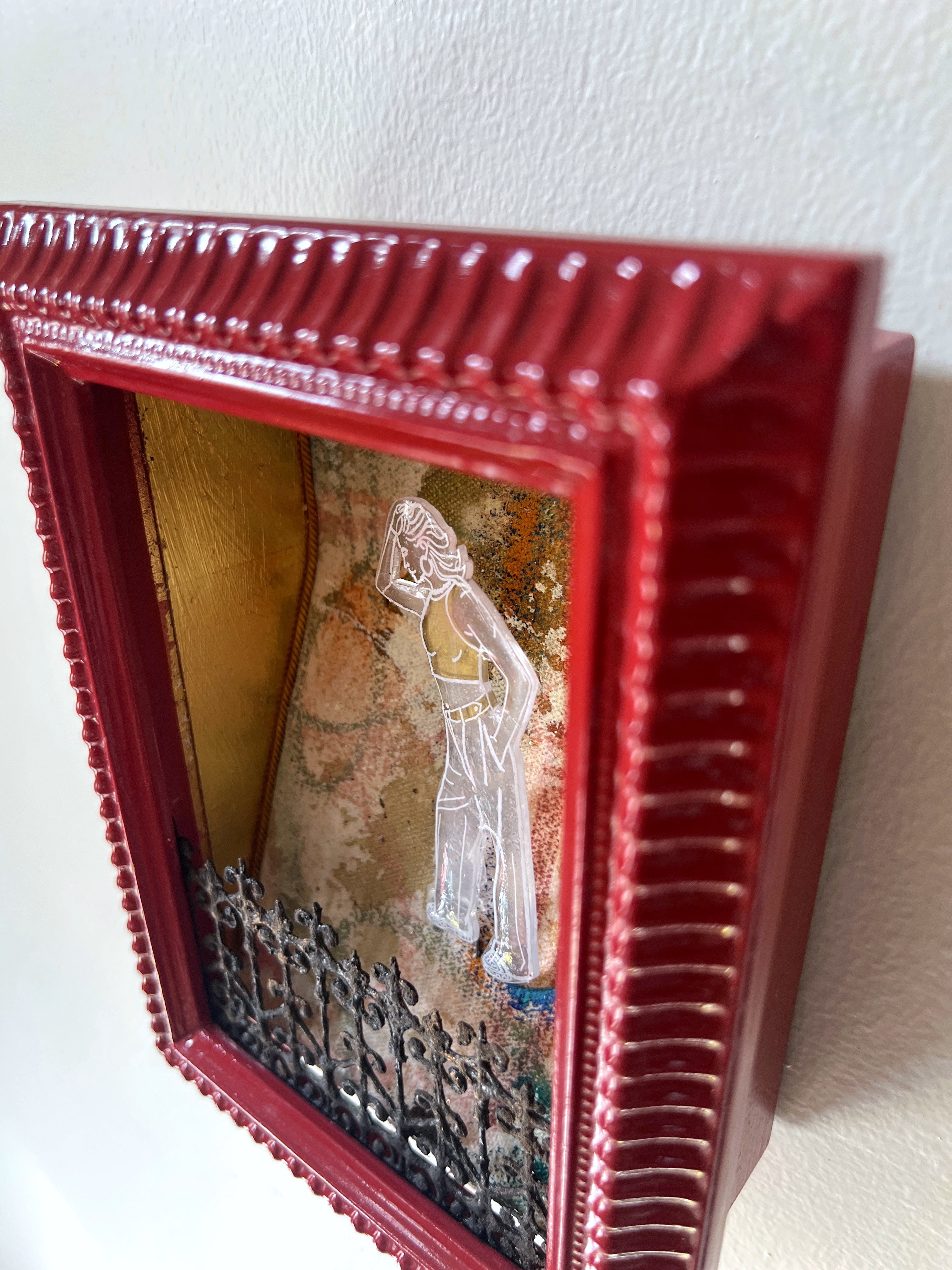 Decorative red frame with a stylized figure and textured background on a white wall.