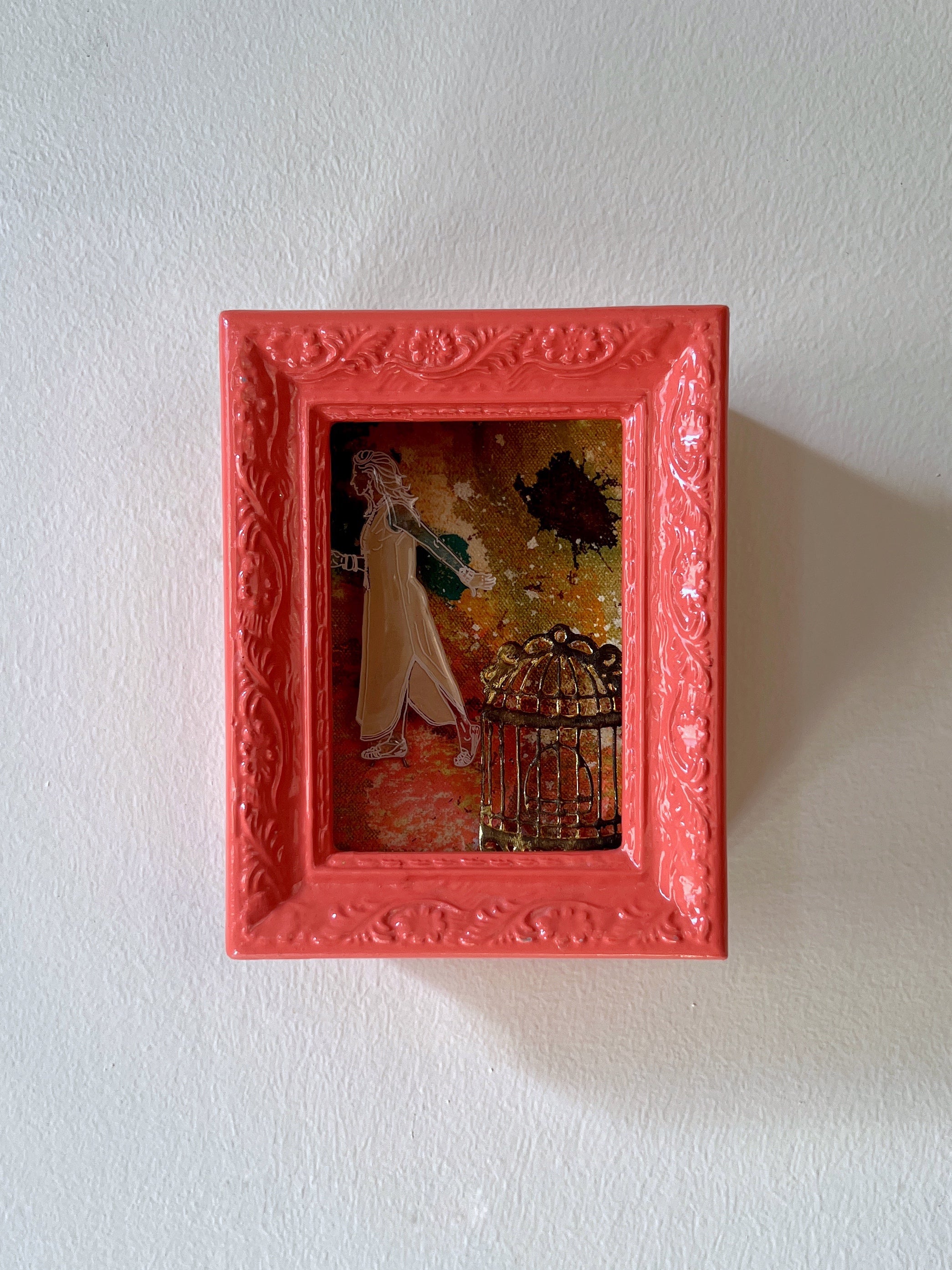 Small framed artwork with a red border on a white wall