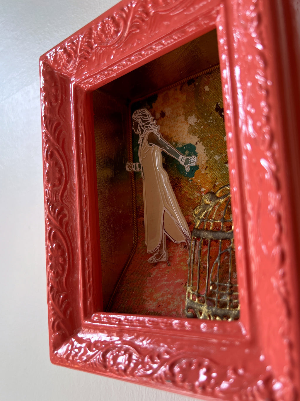 Decorative red shadow box with intricate designs reflecting a room interior.