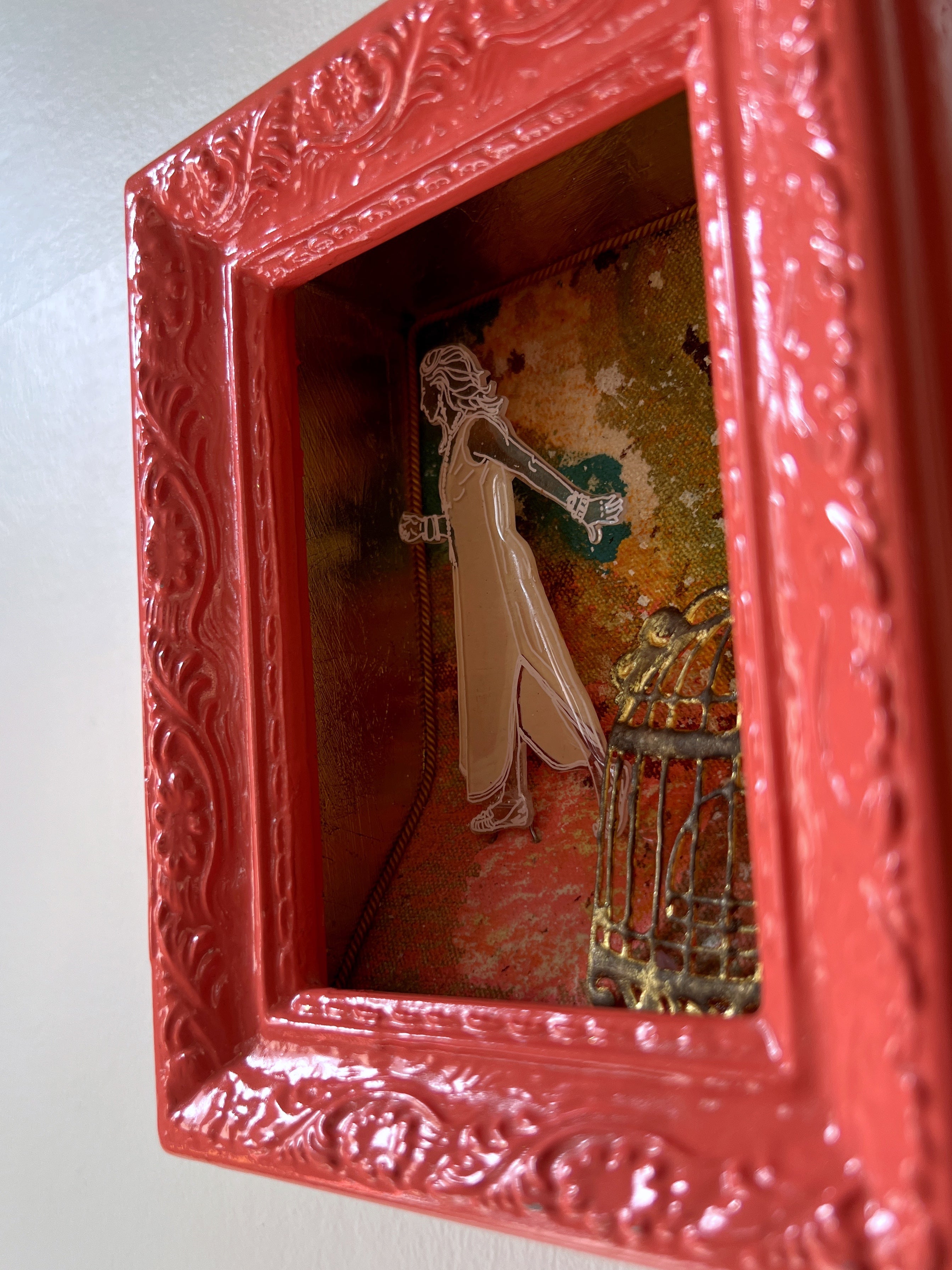 Decorative red shadow box with intricate designs reflecting a room interior.