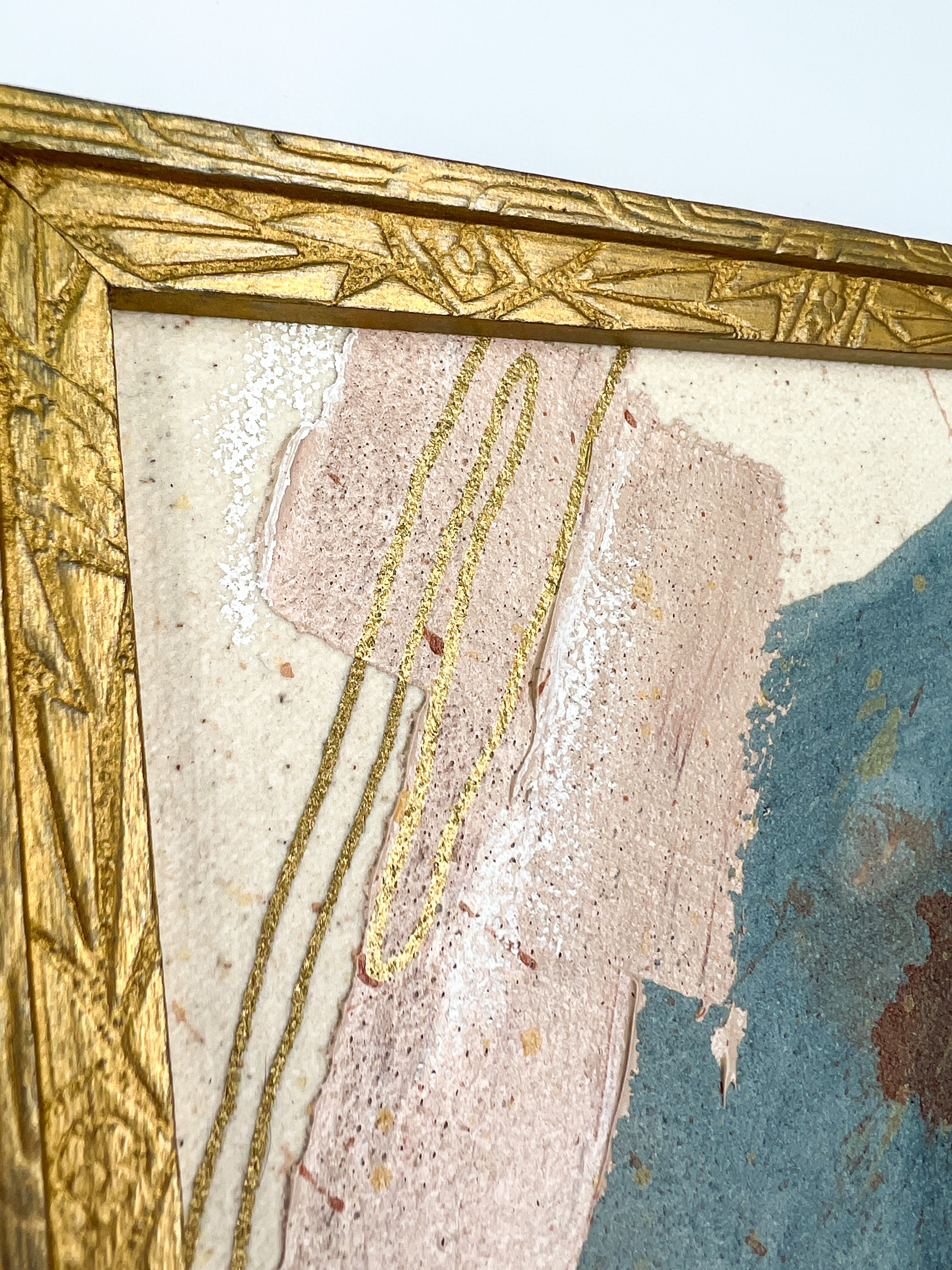 Close-up of a painted canvas with a decorative gold frame.